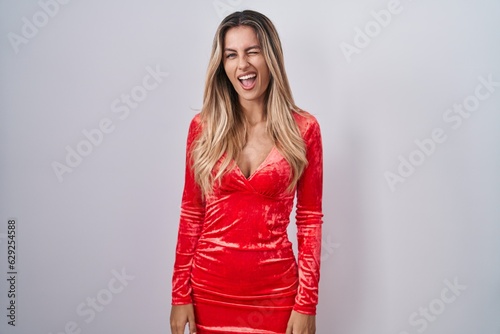 Young blonde woman wearing sexy party dress winking looking at the camera with sexy expression, cheerful and happy face. © Krakenimages.com