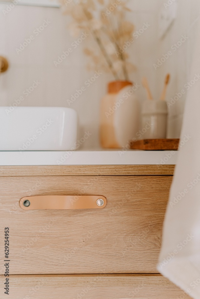 Modern wood bathroom vanity with a white porcelain sink and a white hand towel