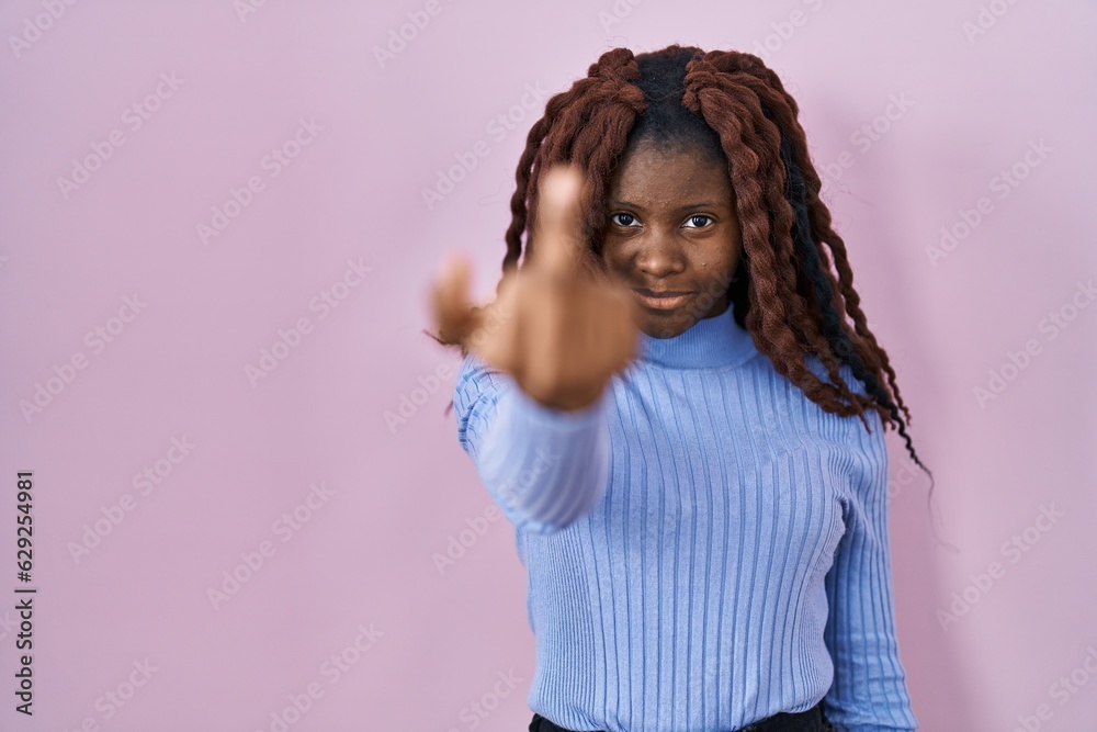 African woman standing over pink background showing middle finger, impolite and rude fuck off expression African woman standing over pink background showing middle finger, impolite and rude fuck off expression