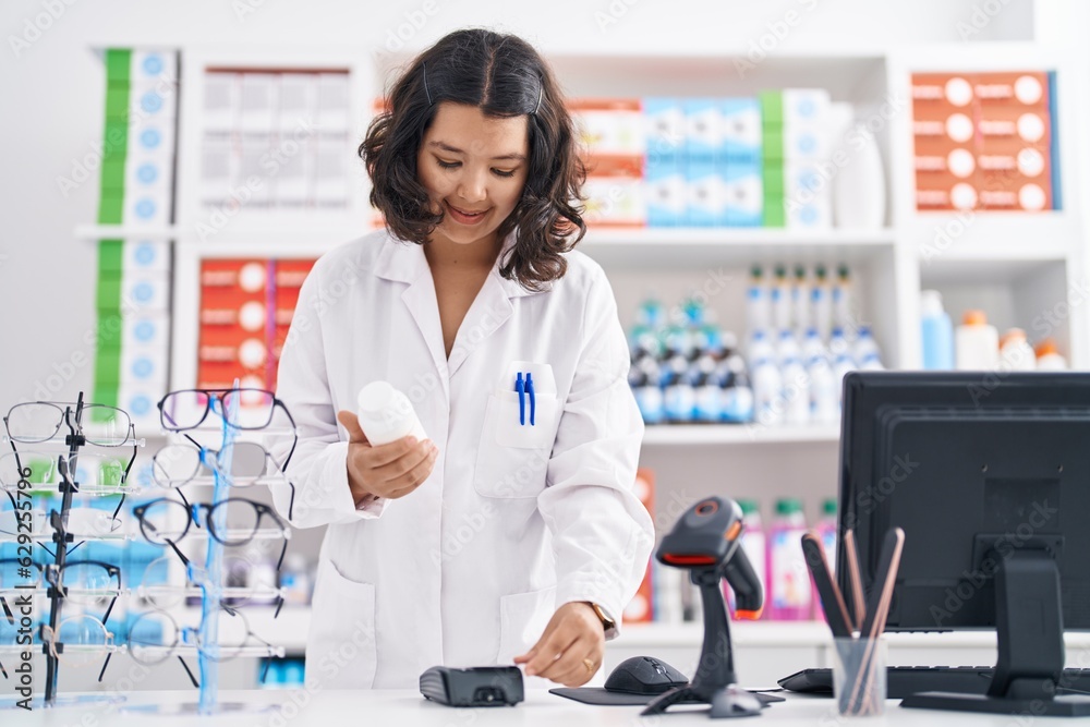 Young woman pharmacist holding pills bottle using credit card at pharmacy Young woman pharmacist holding pills bottle using credit card at pharmacy