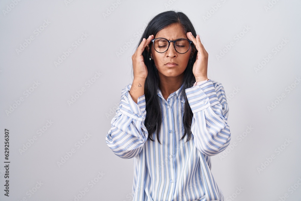 Young hispanic woman wearing glasses with hand on head, headache because stress. suffering migraine. Young hispanic woman wearing glasses with hand on head, headache because stress. suffering migraine.