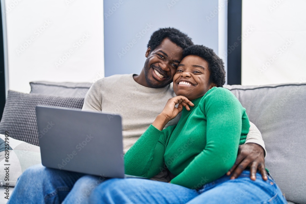 African american man and woman couple using laptop sitting on sofa at home African american man and woman couple using laptop sitting on sofa at home