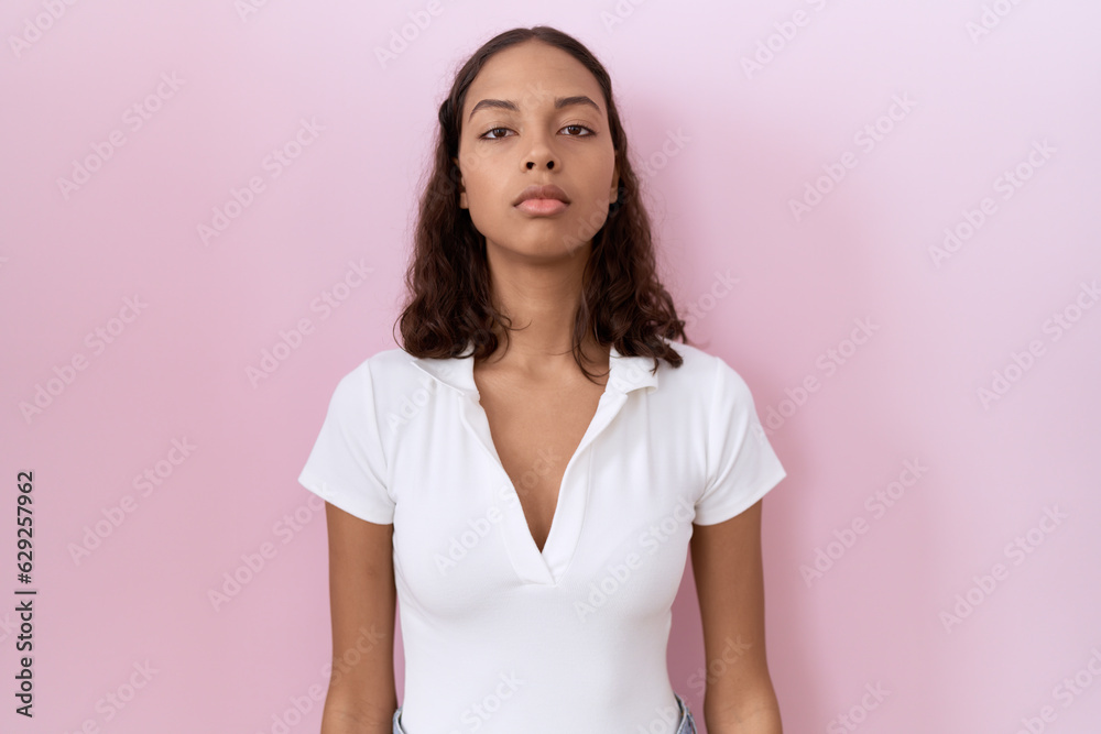 Young hispanic woman wearing casual white t shirt relaxed with serious expression on face. simple and natural looking at the camera. Young hispanic woman wearing casual white t shirt relaxed with serious expression on face. simple and natural looking at the camera.