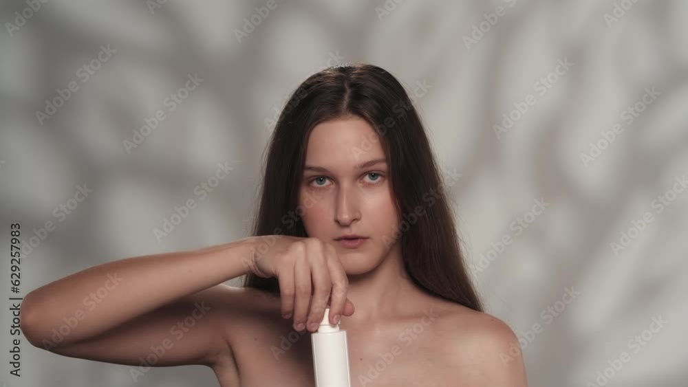 Young female model with fresh skin and natural makeup with a bottle of cosmetic product. Slow motion Young female model with fresh skin and natural makeup with a bottle of cosmetic product. Slow motion