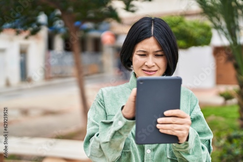 Young chinese woman smiling confident drawing on touchpad at park