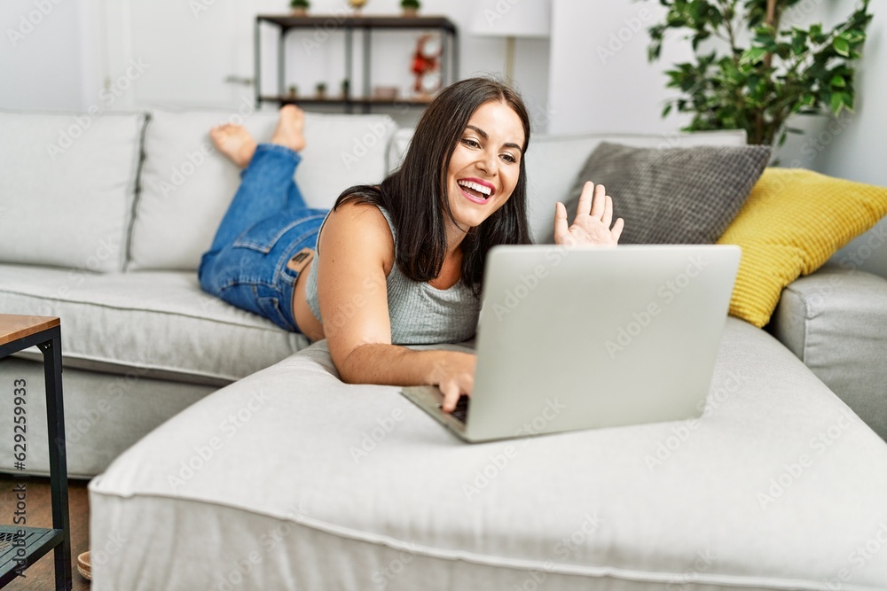 Young beautiful hispanic woman having video call lying on sofa at home Young beautiful hispanic woman having video call lying on sofa at home