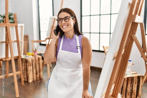 Young beautiful hispanic woman artist smiling confident talking on smartphone at art studio