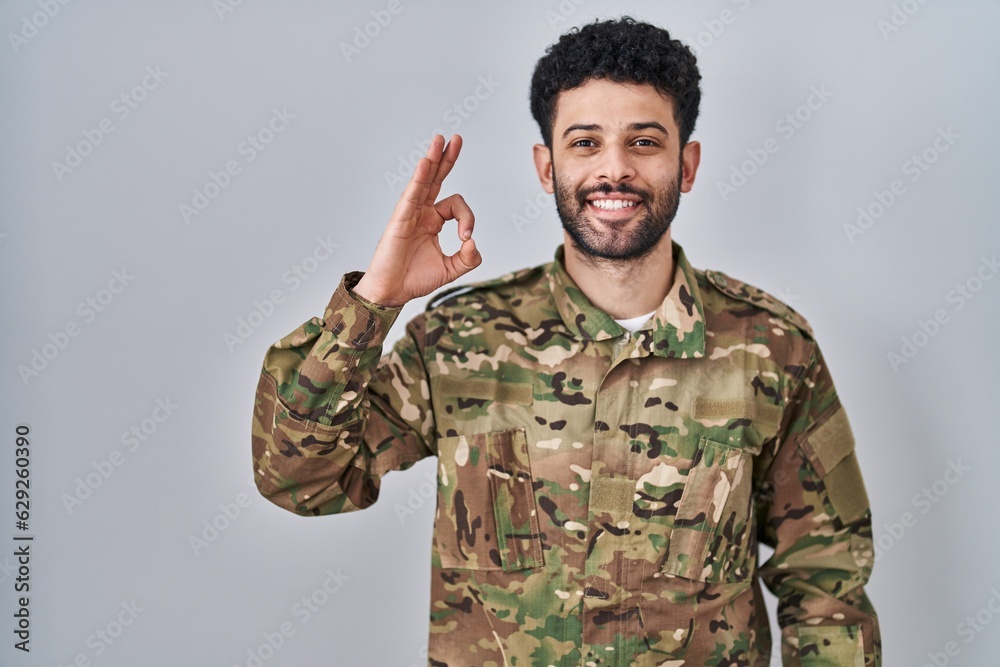 Arab man wearing camouflage army uniform smiling positive doing ok sign with hand and fingers. successful expression. Arab man wearing camouflage army uniform smiling positive doing ok sign with hand and fingers. successful expression.