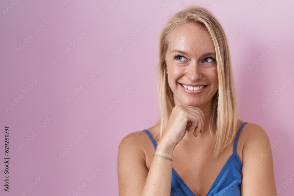 Young caucasian woman standing over pink background with hand on chin thinking about question, pensive expression. smiling and thoughtful face. doubt concept. Young caucasian woman standing over pink background with hand on chin thinking about question, pensive expression. smiling and thoughtful face. doubt concept.