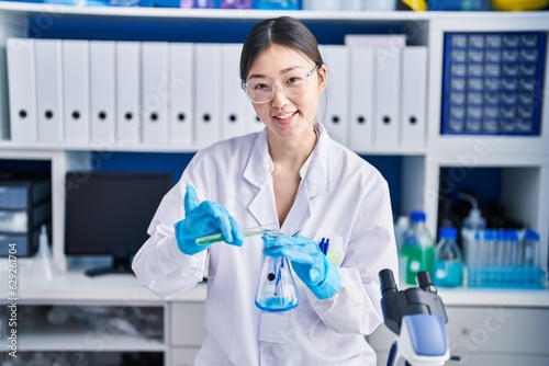 Fotografie Chinese woman scientist pouring liquid on test tube at laboratory
