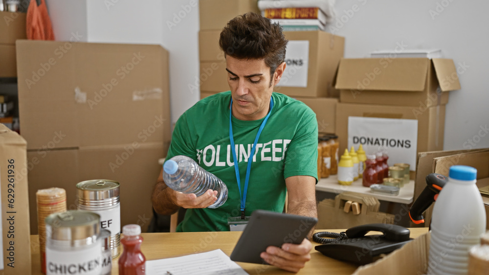 Young hispanic man volunteer using touchpad checking products at charity center Young hispanic man volunteer using touchpad checking products at charity center