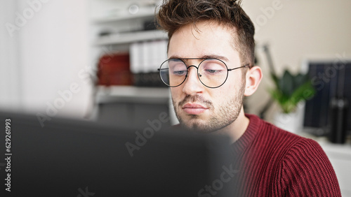 Fototapeta Naklejka Na Ścianę i Meble -  Young hispanic man business worker using laptop with serious face at office