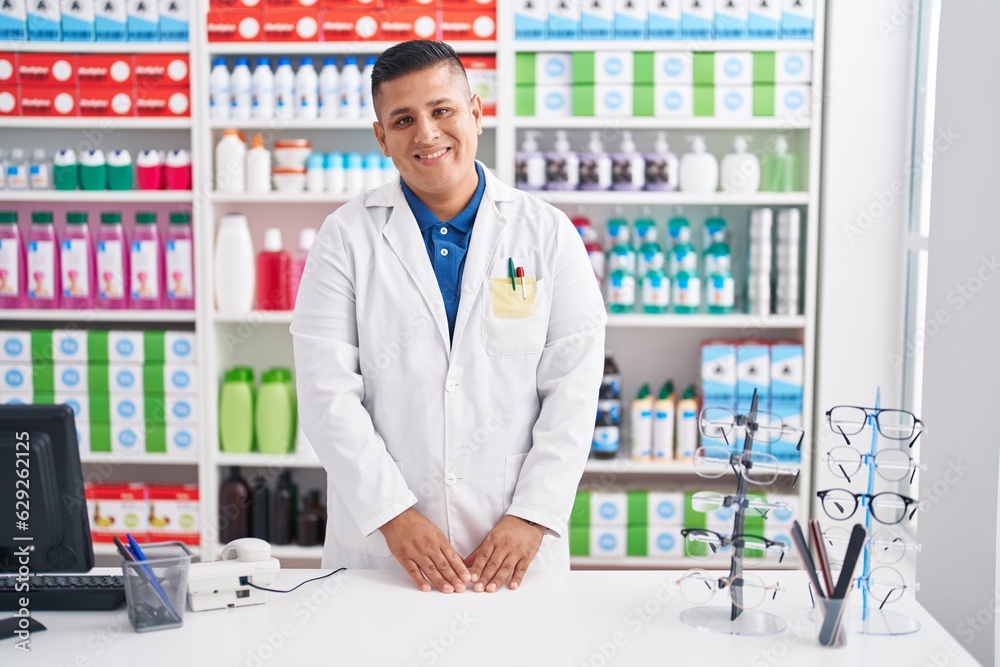 Young latin man pharmacist smiling confident standing at pharmacy