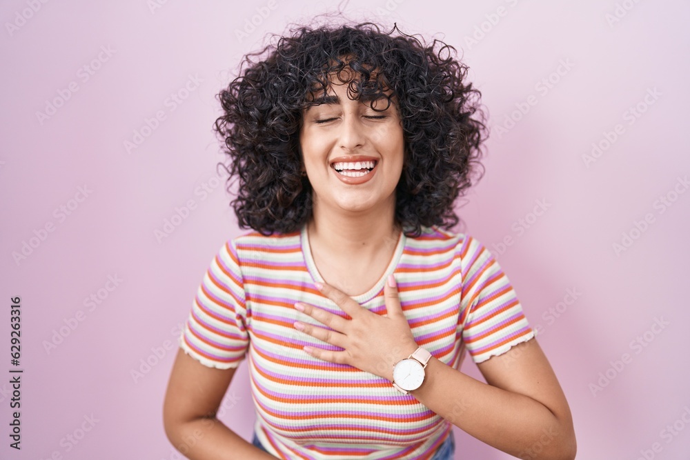 Young middle east woman standing over pink background smiling and laughing hard out loud because funny crazy joke with hands on body. Young middle east woman standing over pink background smiling and laughing hard out loud because funny crazy joke with hands on body.