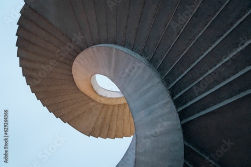 Fototapeta Low angle shot of curved spiral stairs under a bright blue sky