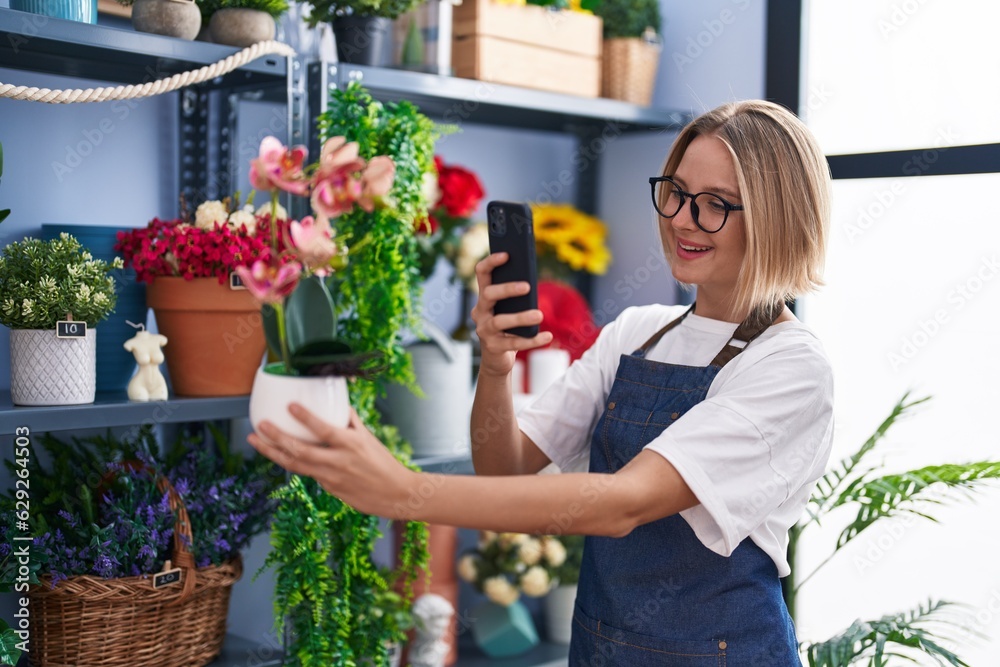 Young blonde woman florist make photo by smartphone to plant at florist shop