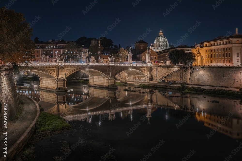 Beautiful view of a bridge over the Tiber River at night in Rome, Italy