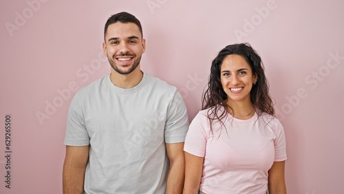 Man and woman couple smiling confident standing together over isolated pink background