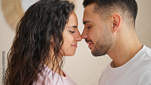 Man and woman couple standing together touching nose at bedroom