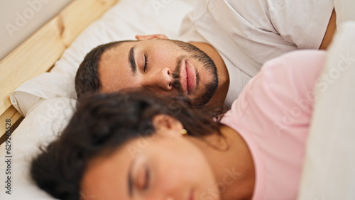 Man and woman couple lying on bed sleeping at bedroom