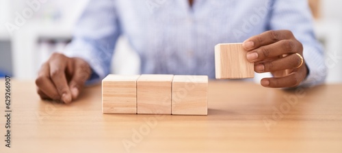 Middle age african american woman business worker sitting on table with wooden cubes at office
