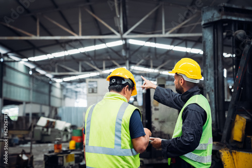 Industrious Engineer Operating Forklift in Warehouse. Efficient Forklift Driving in Factory. Engineer is working and maintaining in the factory. © NewSaetiew