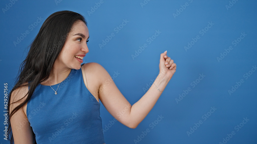Young beautiful hispanic woman smiling confident looking to the side over isolated blue background Young beautiful hispanic woman smiling confident looking to the side over isolated blue background
