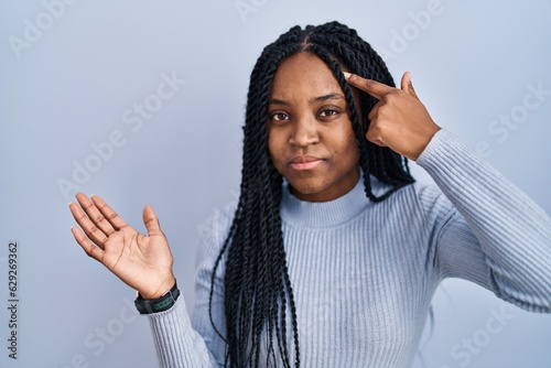 African american woman standing over blue background confused and annoyed with open palm showing copy space and pointing finger to forehead. think about it. © Krakenimages.com