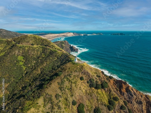 Wallpaper Mural Aerial view of sea waves crashing against green coastal mountains on a sunny day Torontodigital.ca