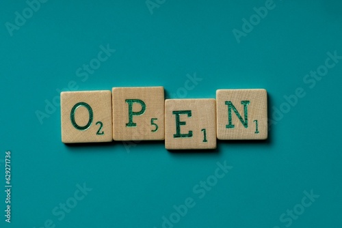 Wooden letters spelling the word "open" on a blue background.