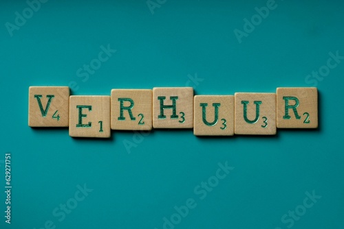 Wooden letters spelling the word "verhuur" (dutch for renting) on a blue background