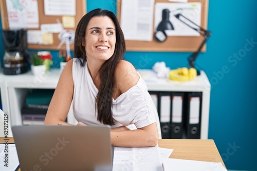 Young beautiful hispanic woman business worker smiling confident sitting on table at office