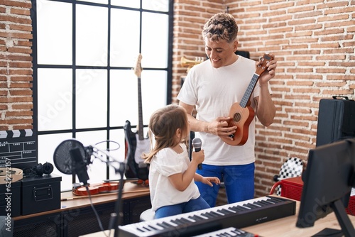 Fototapeta Naklejka Na Ścianę i Meble -  Father and daughter singing song playing ukulele at music studio