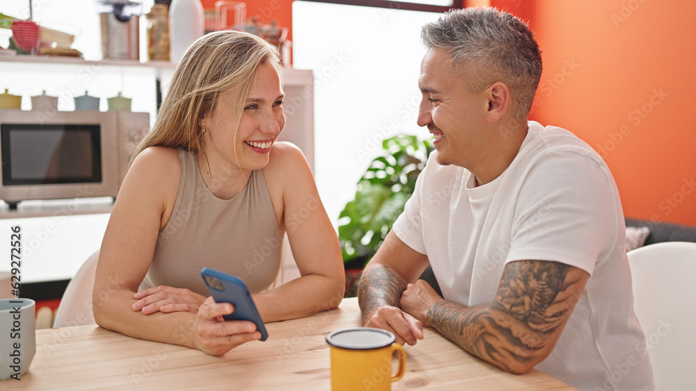 Man and woman couple using smartphone sitting on table at dinning room Man and woman couple using smartphone sitting on table at dinning room