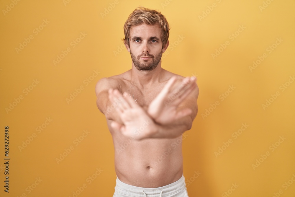 Caucasian man standing shirtless wearing sun screen rejection expression crossing arms and palms doing negative sign, angry face