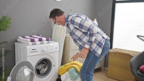 Middle age man washing clothes at laundry room