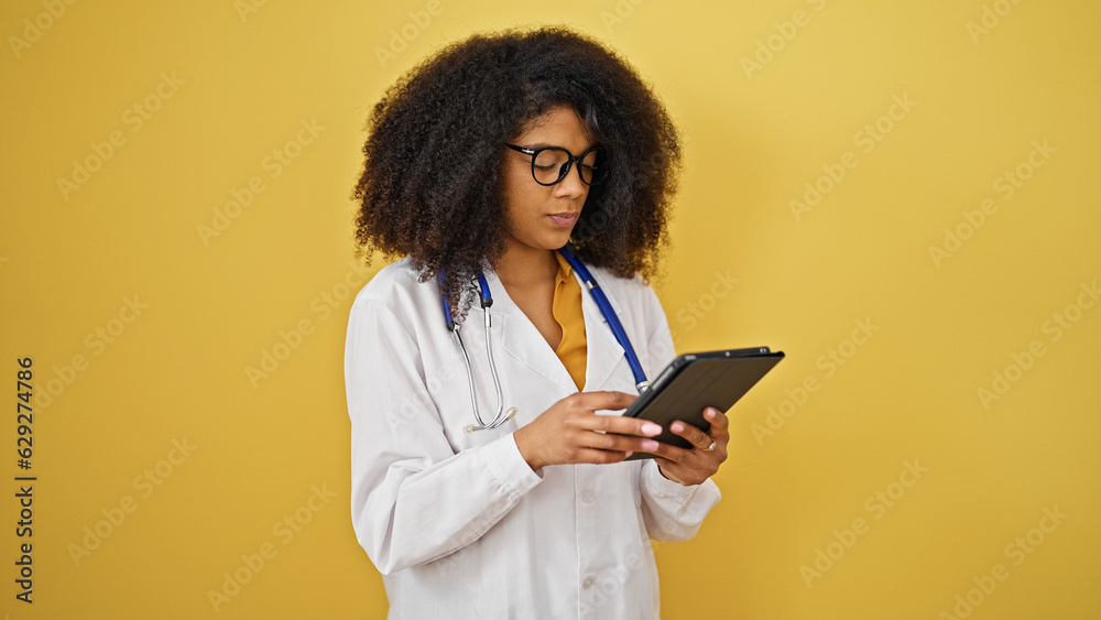 African american woman doctor using touchpad over isolated yellow background African american woman doctor using touchpad over isolated yellow background