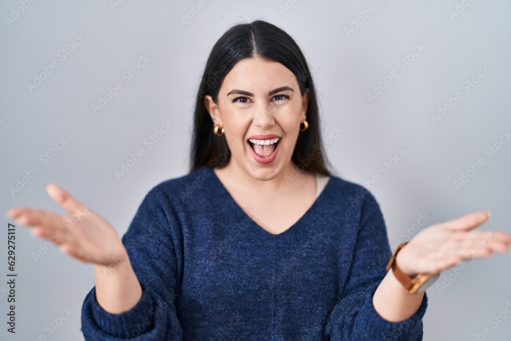 Young brunette woman standing over isolated background smiling cheerful offering hands giving assistance and acceptance. Young brunette woman standing over isolated background smiling cheerful offering hands giving assistance and acceptance.