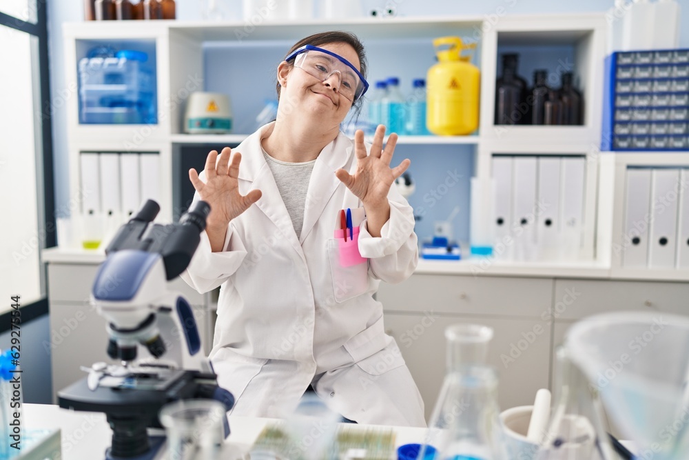 Hispanic girl with down syndrome working at scientist laboratory disgusted expression, displeased and fearful doing disgust face because aversion reaction. Hispanic girl with down syndrome working at scientist laboratory disgusted expression, displeased and fearful doing disgust face because aversion reaction.