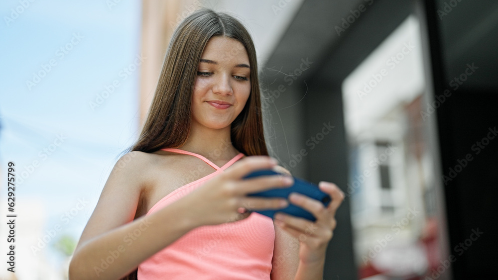 Young beautiful girl smiling confident playing video game at street