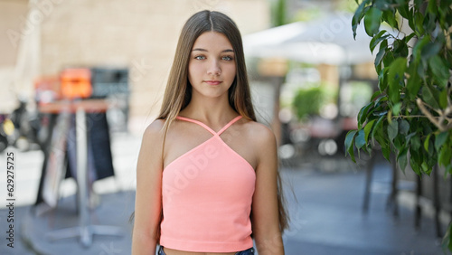 Young beautiful girl standing with serious expression at coffee shop terrace