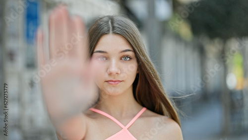 Young beautiful girl doing stop gesture with hand at street