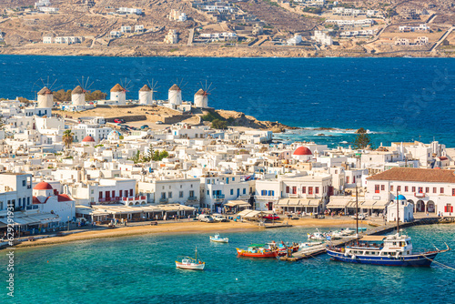 Chora port of Mykonos island with red church, famous windmills, ships and yachts during summer sunny day. Aegean sea, Greece photo
