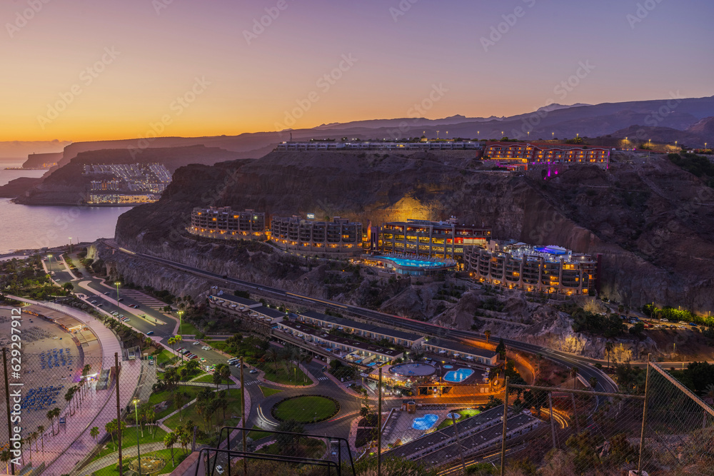 Beautiful view of mountainous coast of Gran Canaria overlooking city and sandy beach at sunset. Spain.