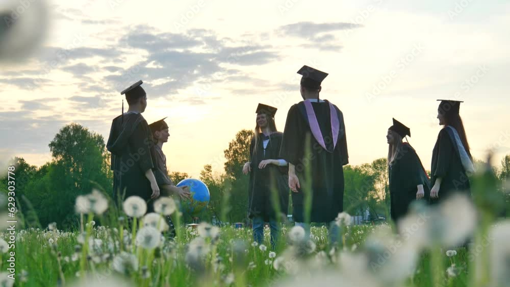 Graduates in costume playing with a ball at sunset.