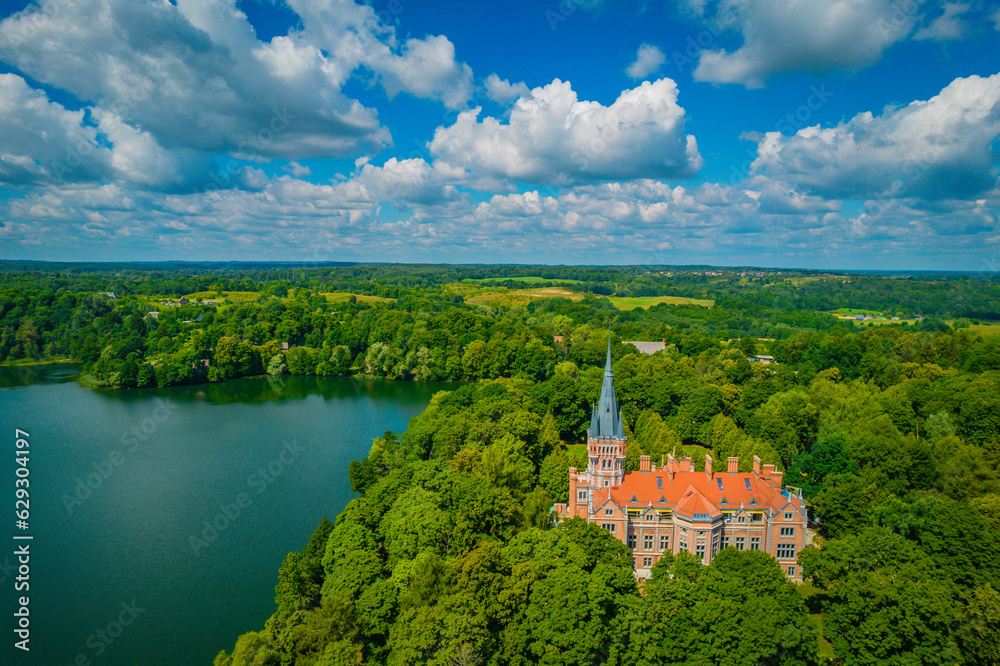 Naklejka premium Palace Tyszkiewicz (Tiskeviciai manor) in Lentvaris on the coast of the lake, Lithuania. Aerial view of Tudor style castle