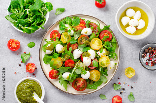 Caprese Salad with Cherry Tomatoes and Pesto Sauce over Bright Background