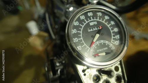 Close-up of speedometer with chrome bezel and odometer on a vintage motorcycle with shiny metal in a garage. Marking in miles per hour. Bike repair in the workshop photo