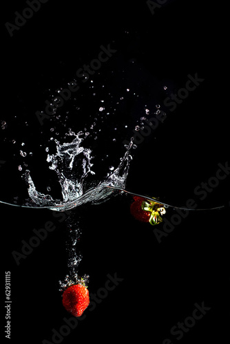 bright juicy fruits with splashes fly into the aquarium on a black background.
