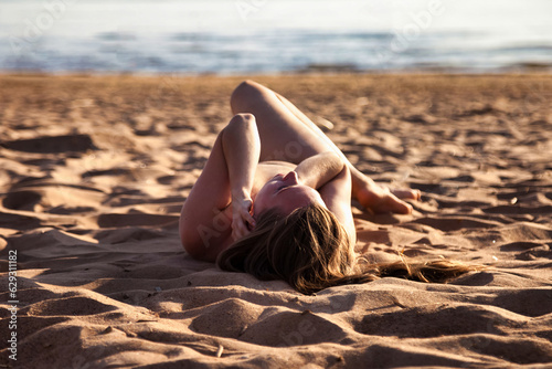 Perfect nude naturist lady posing lying on nudist public sea beach, relaxing. Naked lovely woman with sexy body, no clothing. Nudism naturism lifestyle concept, clothes optional. Copy ad text space